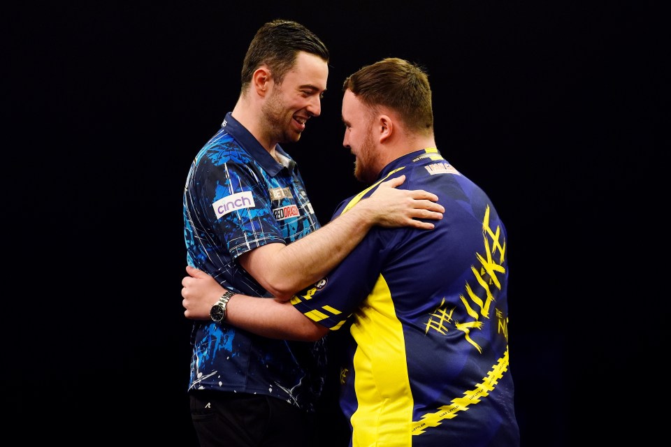 Luke Humphries and Luke Littler embracing at a darts tournament.