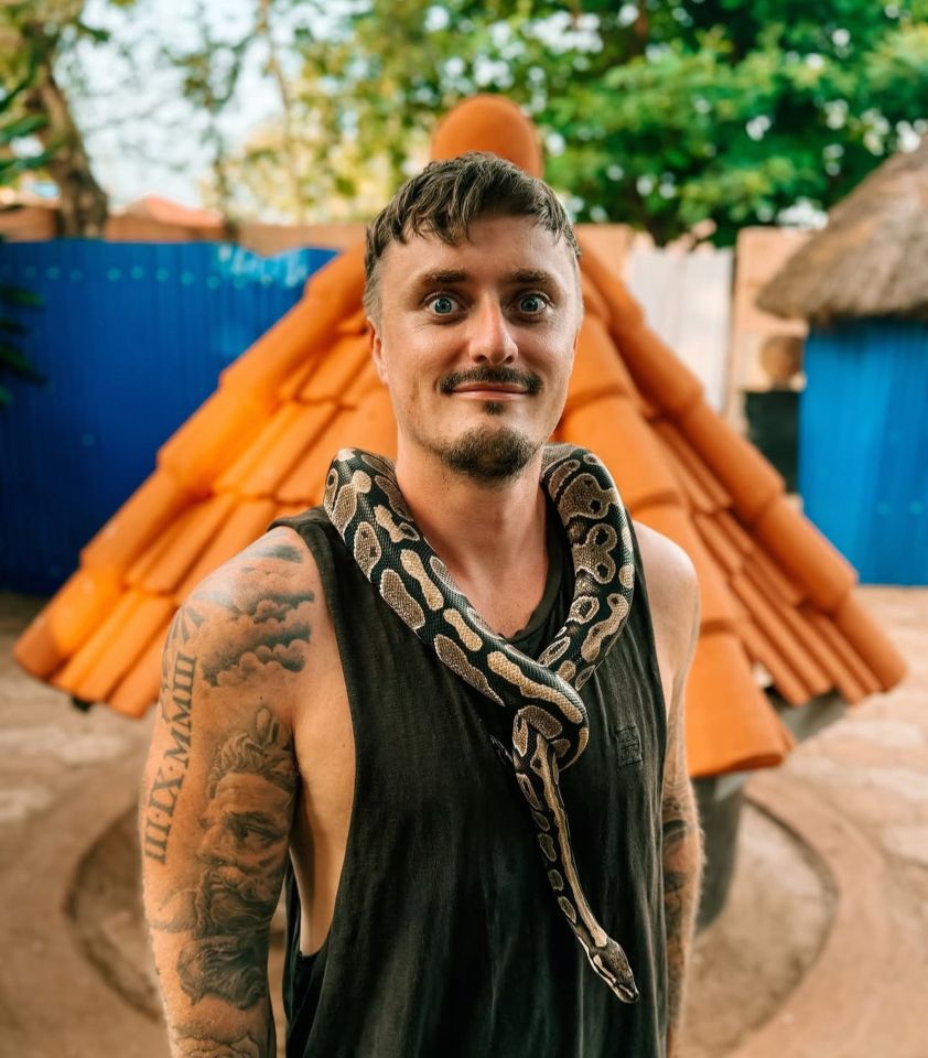 Man with tattoos and a snake around his neck in Ouidah, Benin.