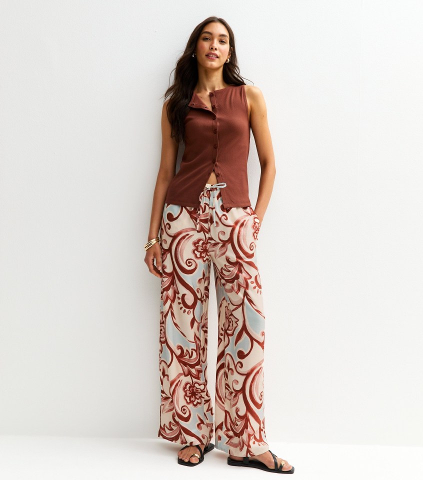 Woman wearing brown sleeveless top and wide-leg paisley pants.