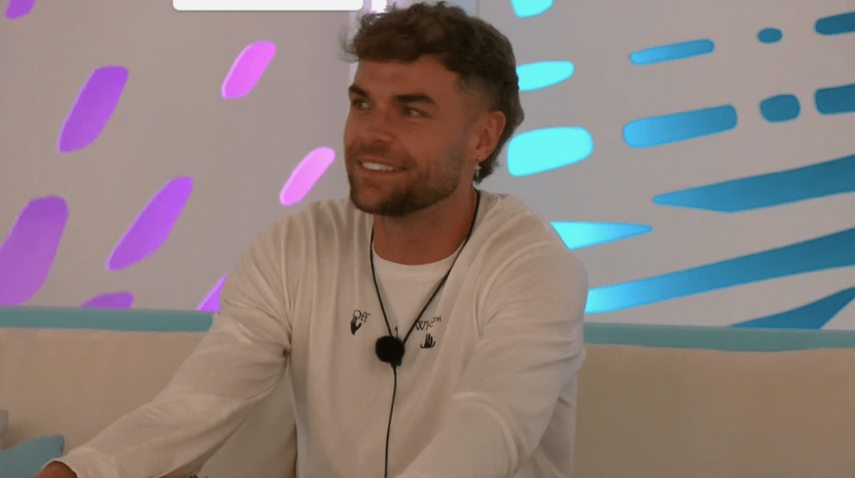 Screenshot of a man sitting on a couch.