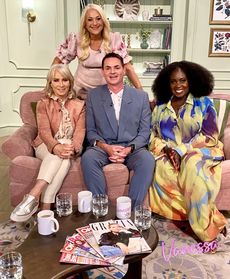 Four people sitting on a pink couch on a TV show set.
