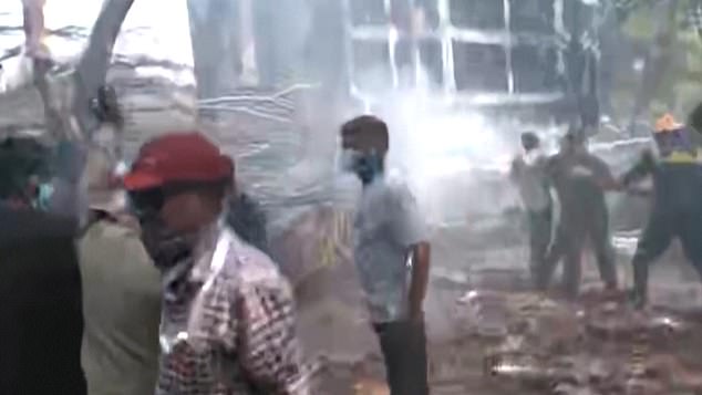 Shocked residents are seen standing close to the scene as firefighters work to extinguish flames
