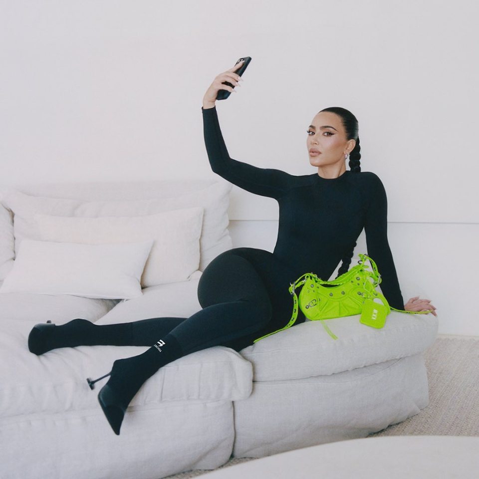 a woman sitting on a couch taking a selfie with her phone