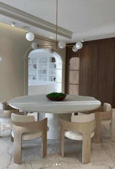 Dining room with large round table and light wood chairs.