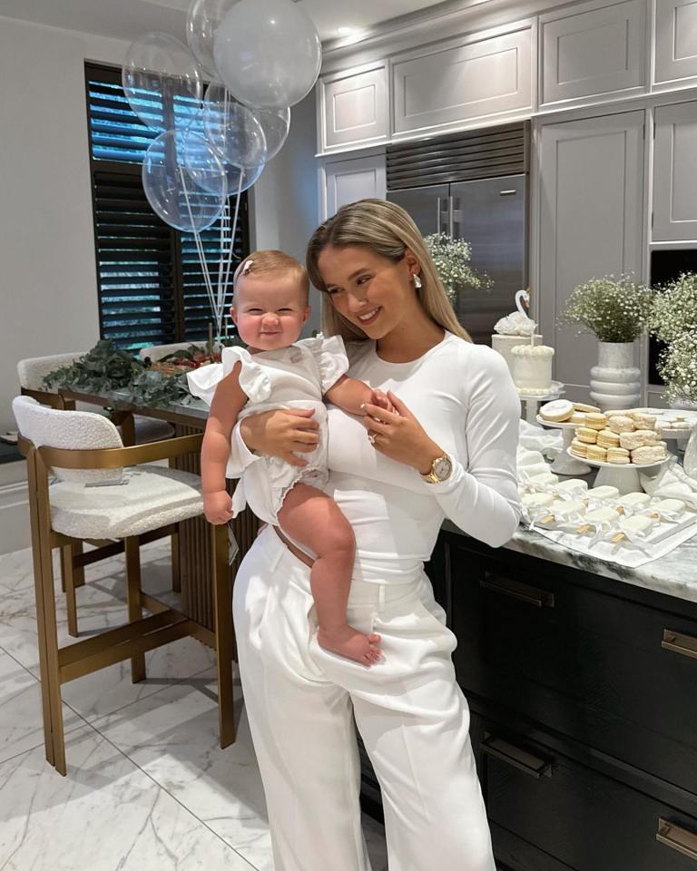 Molly-Mae holding her baby at a first birthday party.