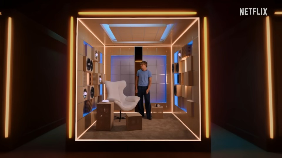 A man standing in a soundproof room with speakers on the walls for Netflix's *Building the Band*.