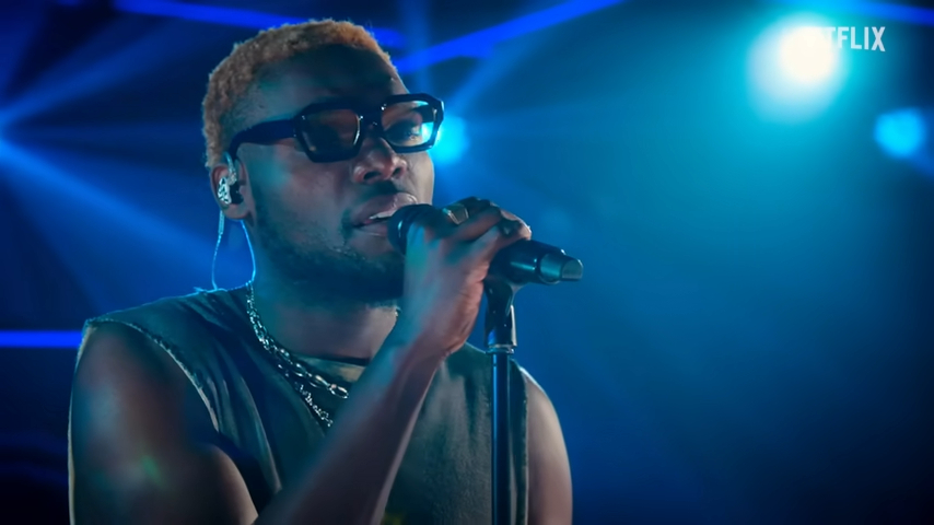 Still of a man singing into a microphone.