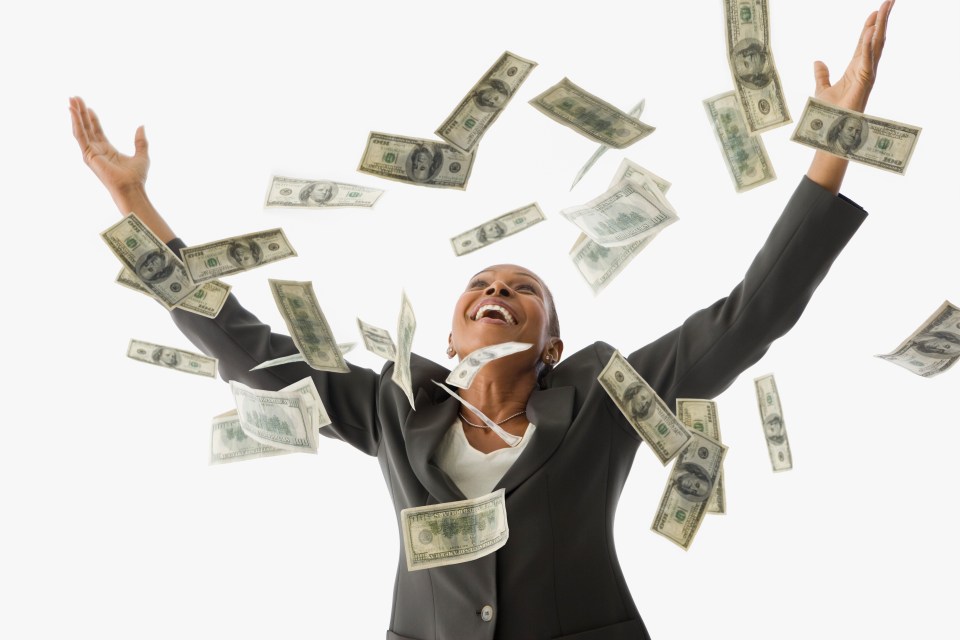 A joyful businesswoman throws money into the air.