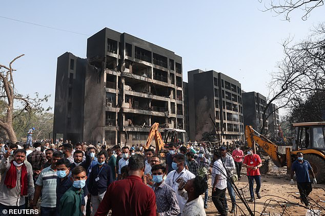 People gather near a damaged building at the site where an Air India Boeing 787 Dreamliner plane crashed in Ahmedabad, India