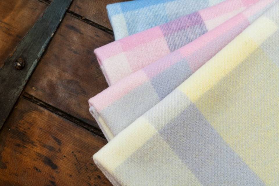 Pastel gingham blankets stacked on wood.