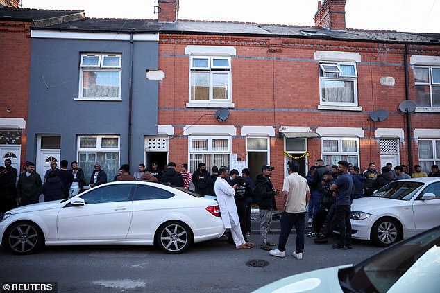 Members of a local community stand outside the Leicester family home of Viswash, the British survivor of the London-bound Air India aircraft crash