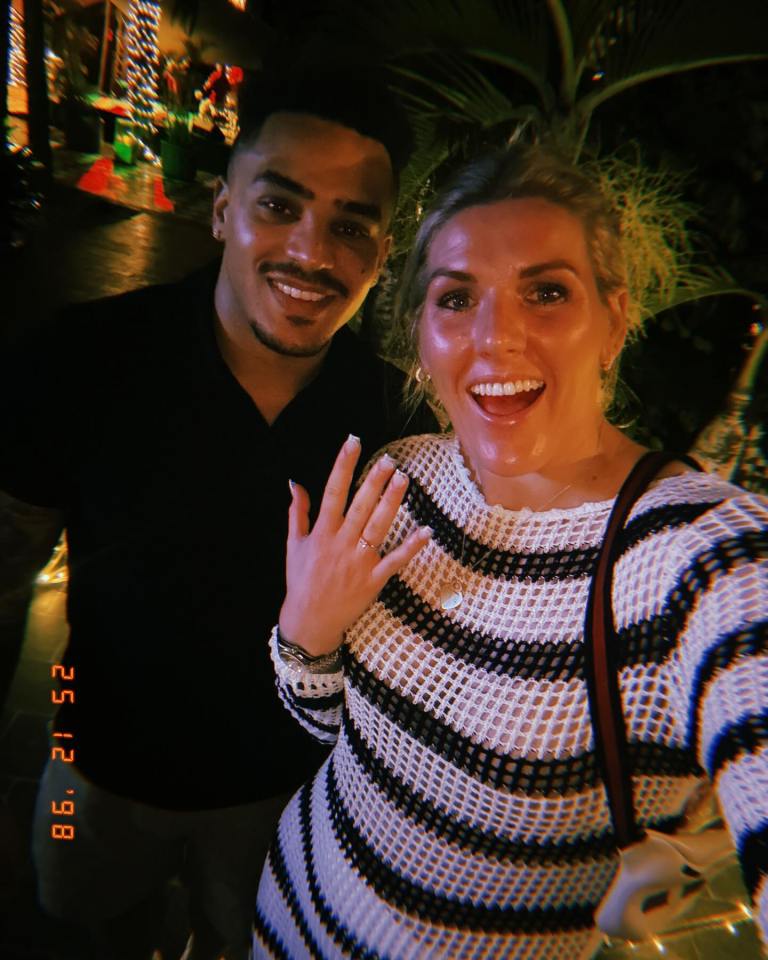 Photo of a couple, the woman showing off her engagement ring.