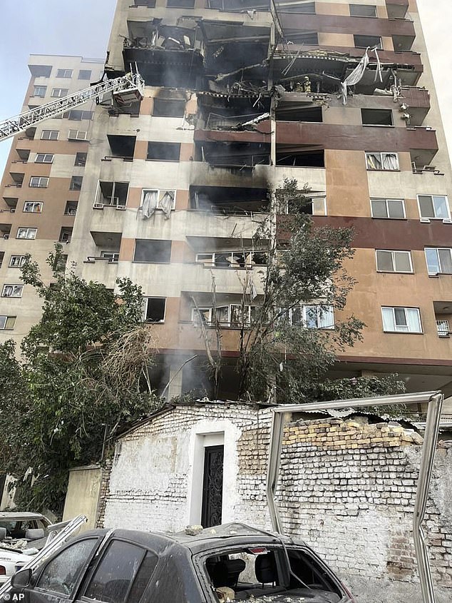 Firemen work at an apartment building after it was hit in Tehran, Iran, early Friday