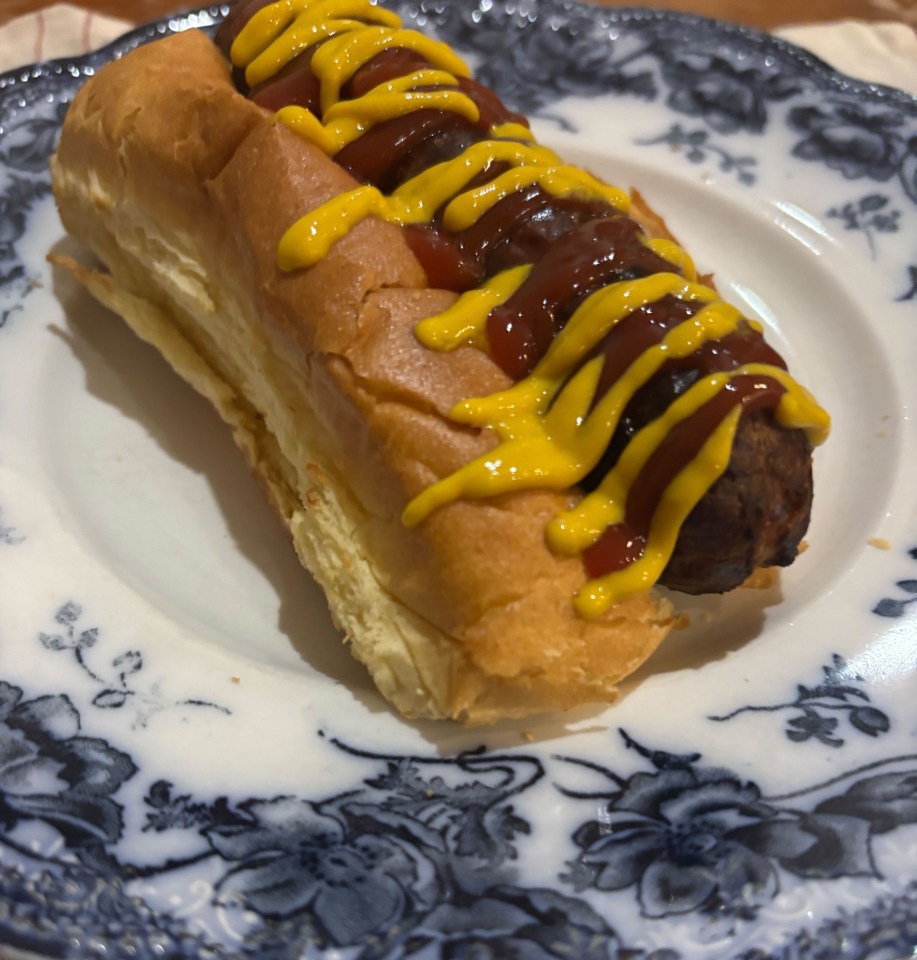 Air fryer BBQ sausage on a bun with ketchup and mustard.