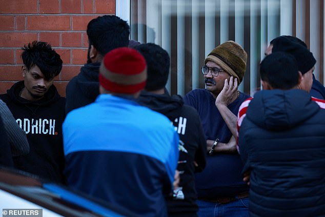 Members of local community stand outside the family home of Viswash, the British survivor of the London-bound Air India aircraft crash