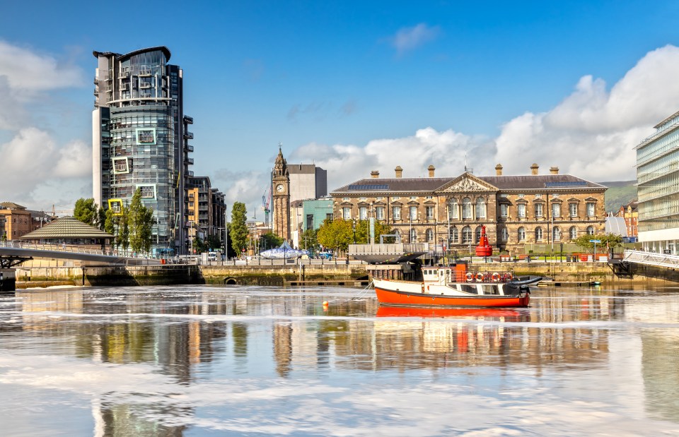 Long exposure photo of the Lagan River in Belfast, with the Custom House and other buildings reflected in the water.
