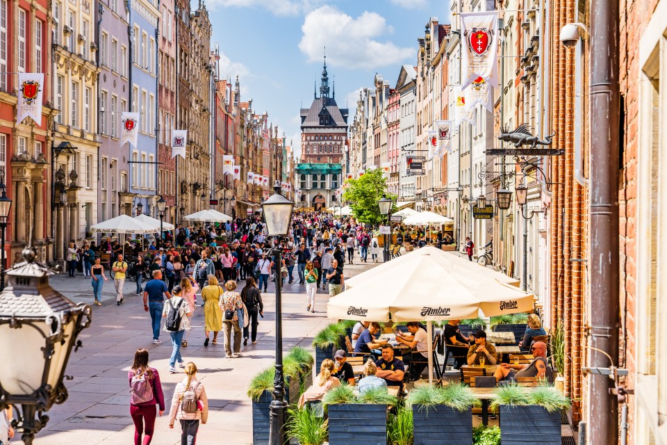 Tourists strolling through Gdansk's Old Town, with cafes and the Golden Gate in the background.