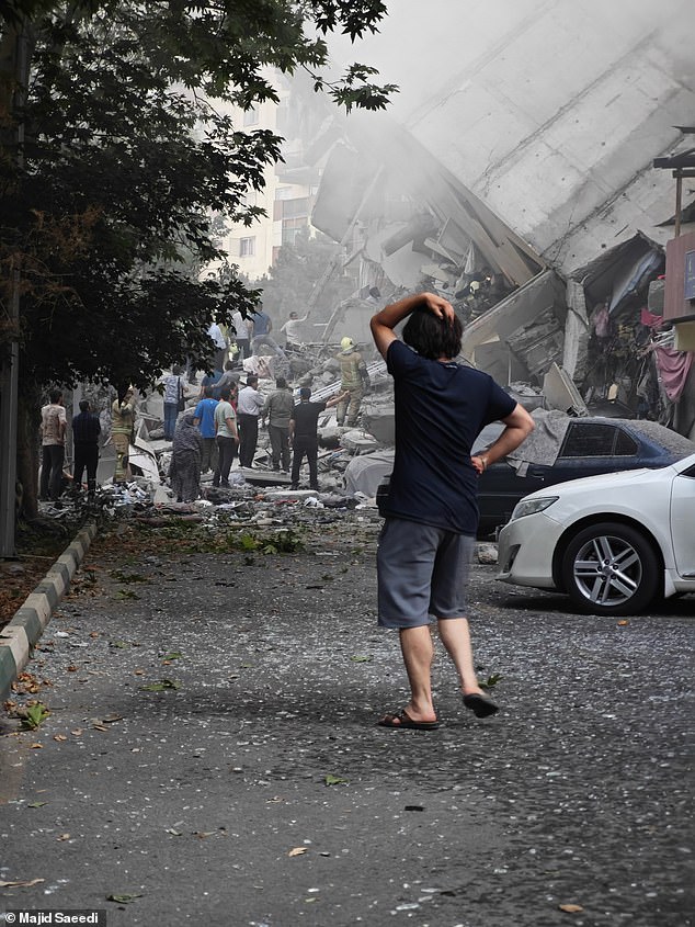 A person reacts as residential buildings in Nobonyad Square are shown following Israeli airstrikes on June 13, 2025 in Tehran, Iran