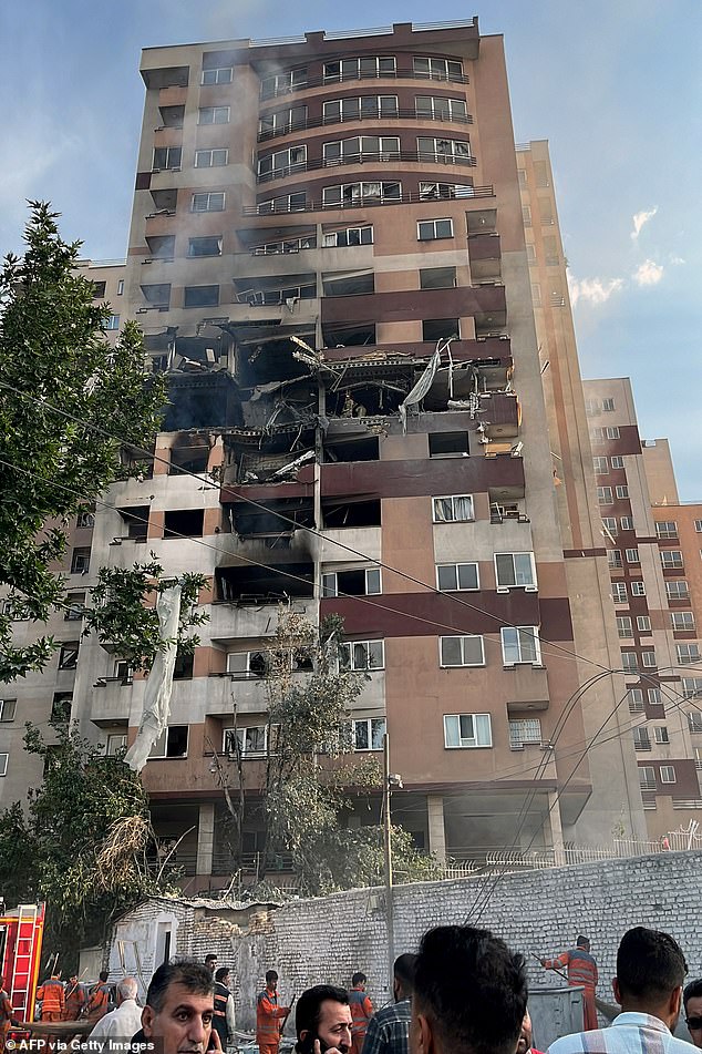 Onlookers gather in front of a building targeted by an Israeli strike on the Iranian capital Tehran on June 13, 2025