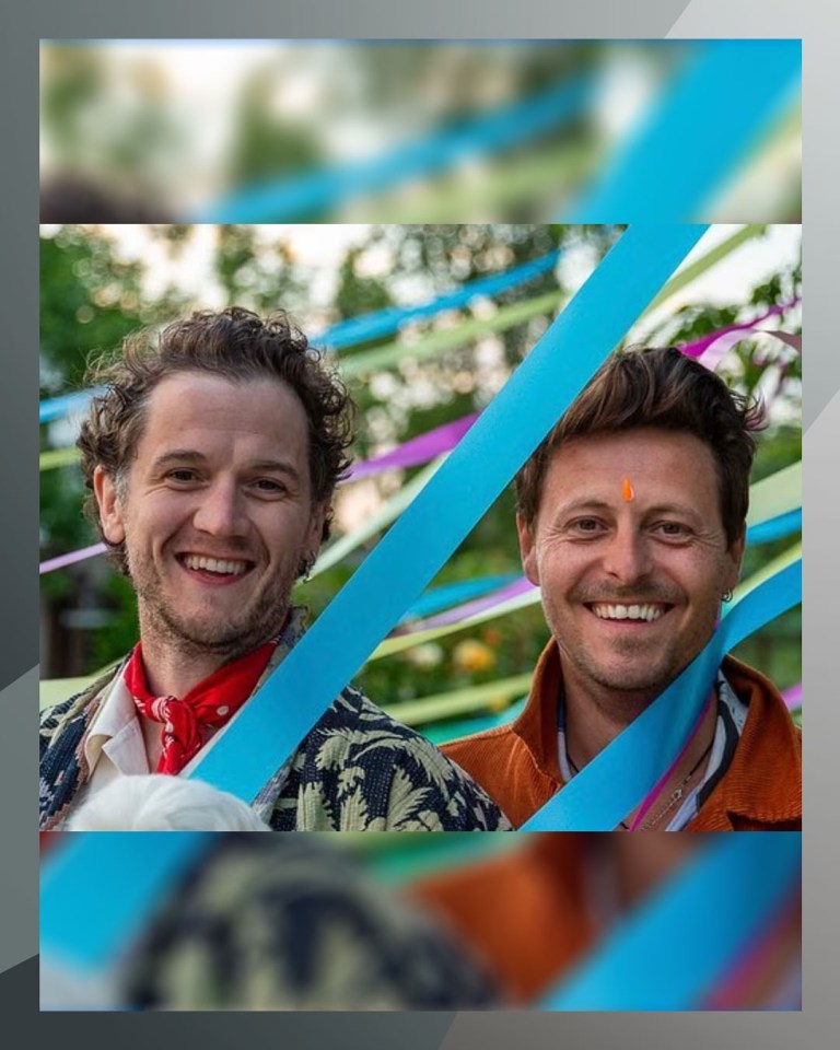 Two men smiling behind colorful ribbons.