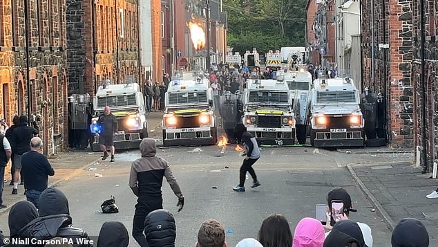 PSNI vehicles form a barricade as they face off with rioters on the streets of Ballymena