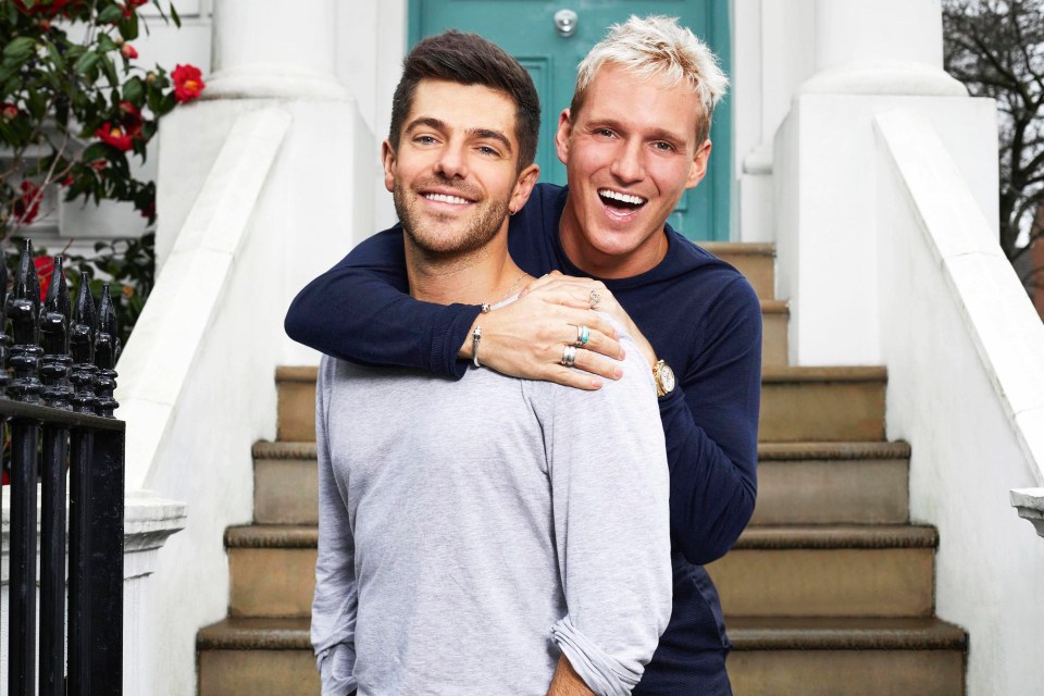 Two men smiling and hugging on a set of stairs.