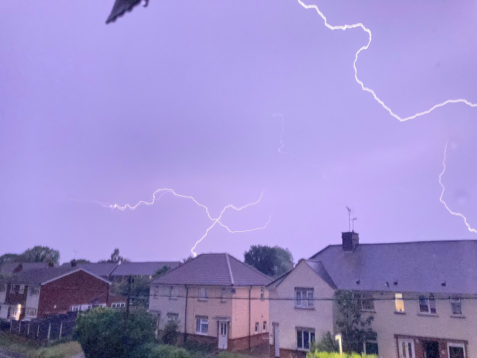 Lightning striking over houses.