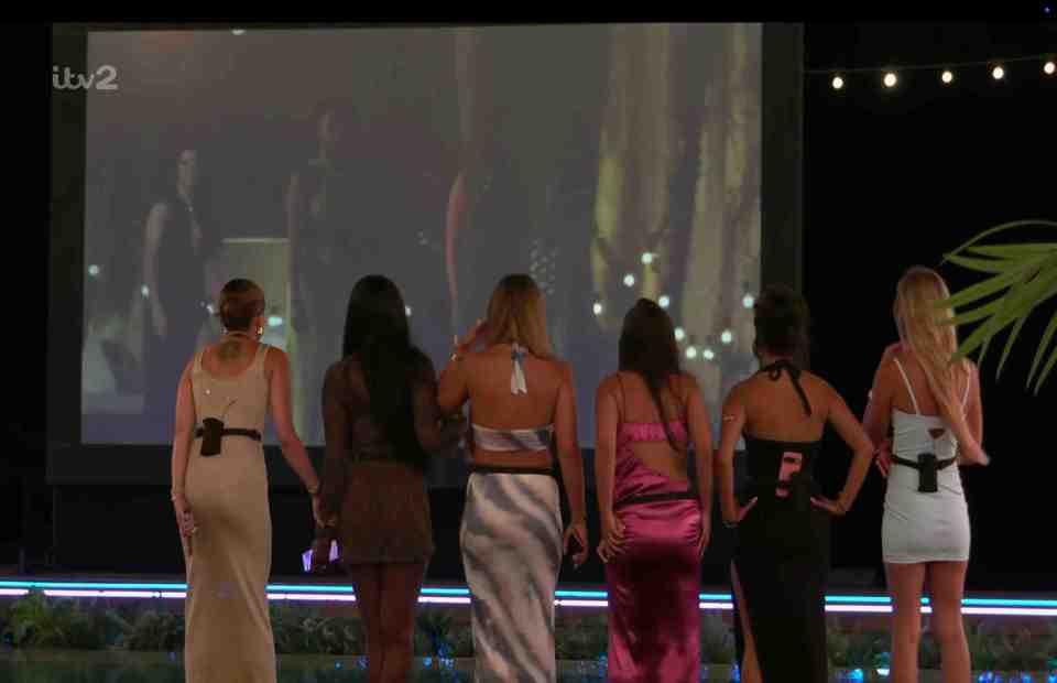 Women watching men on a large screen.