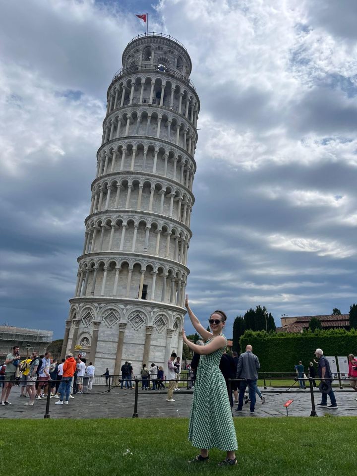 Woman posing in front of the Leaning Tower of Pisa.