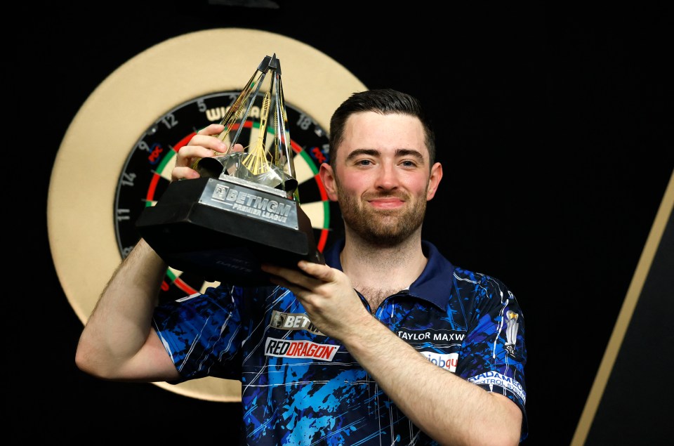 Luke Humphries holding the Premier League Darts trophy.