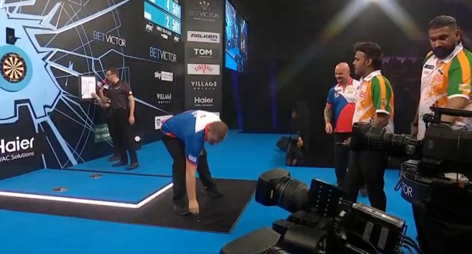 Darts player picking up a dart at a tournament.