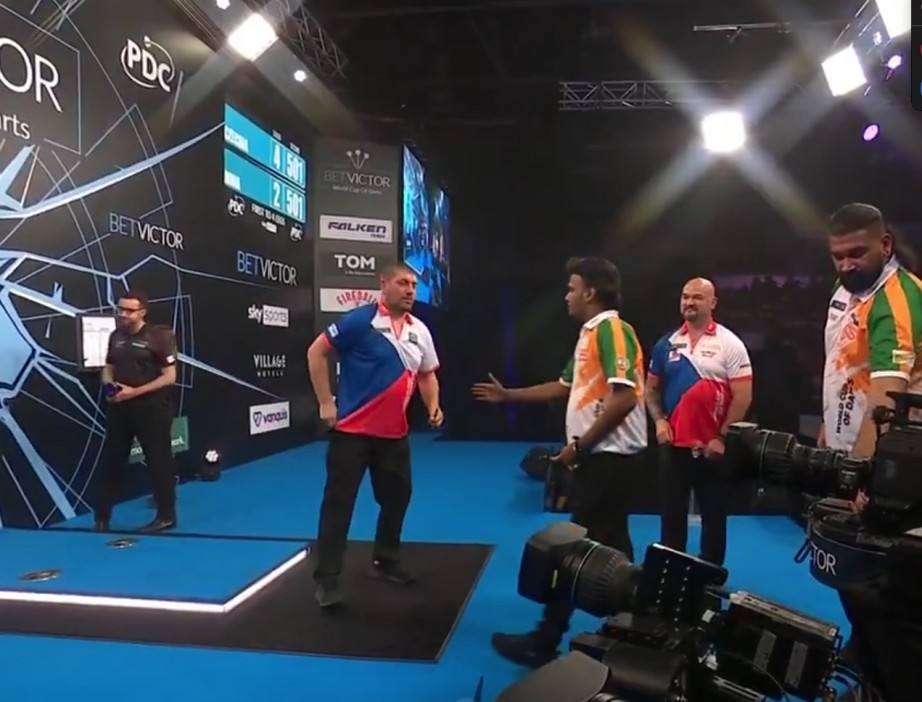 Darts players on stage during a match.