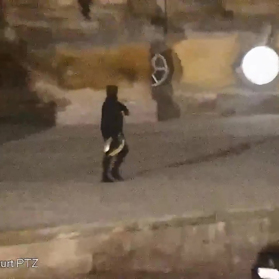 Low-light surveillance image of a suspect walking away.