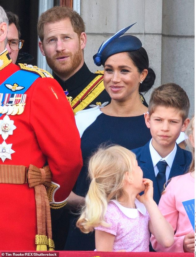 The Duchess wore a navy short-sleeved dress by Givenchy and a matching hat by Noel Stewart as she stood in front of her husband
