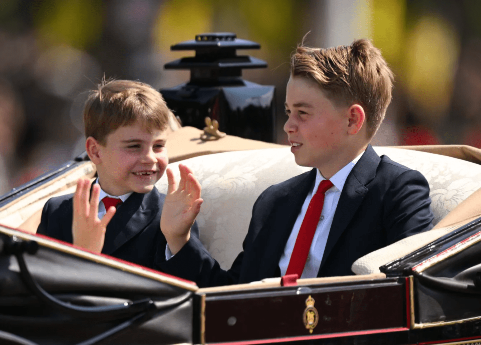 Two young boys in suits waving from a carriage.