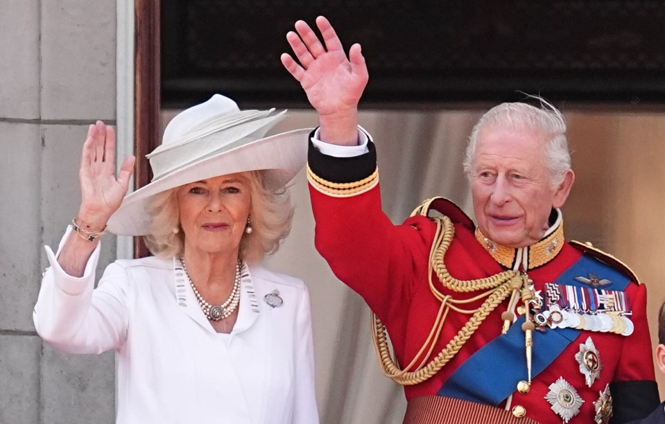 Queen Camilla and King Charles III waving from Buckingham Palace balcony.