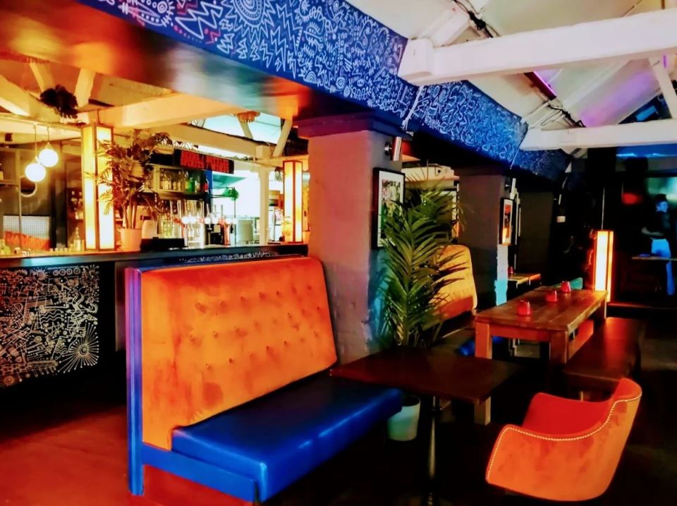 Interior of a bar with orange and blue seating.