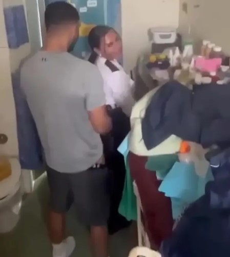 Still image from a video showing a prison officer and an inmate in a prison cell.