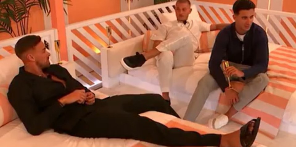 Three men relaxing on beds in a brightly-lit room.