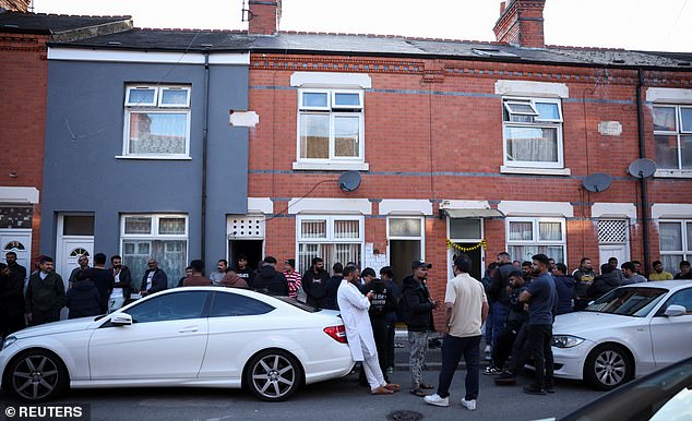 Members of a local community stand outside the Leicester family home of Viswash, the British survivor of the London-bound Air India aircraft crash