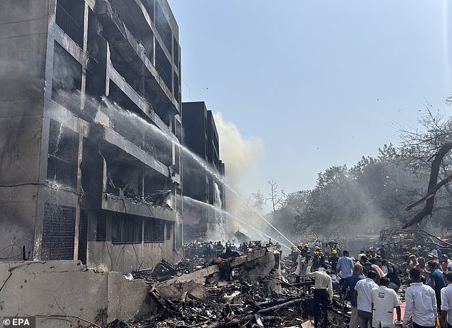Firefighters work at the site of the crash near Sardar Vallabhbhai Patel International Airport