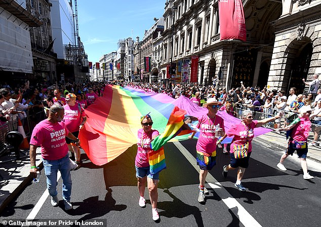 The rainbow flag is carried along Piccadilly by parade-goers during Pride In London 2024