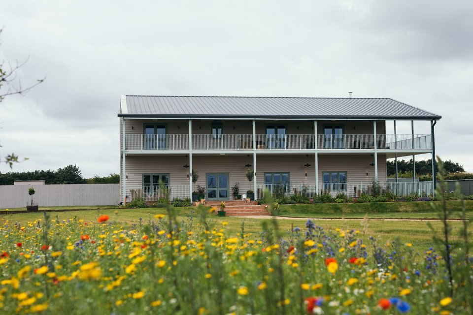 Farmhouse with a wildflower meadow in the foreground.