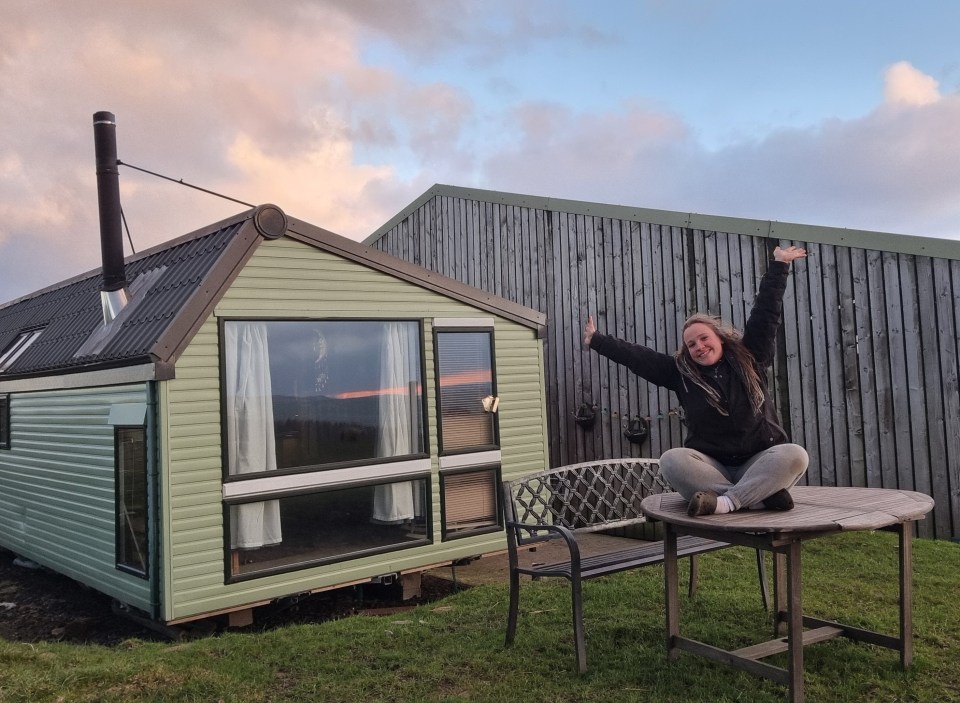 Woman sitting on a table outside a mobile home.