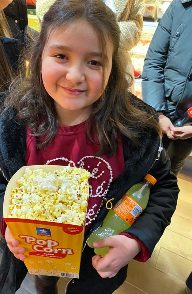 Girl holding popcorn and soda.