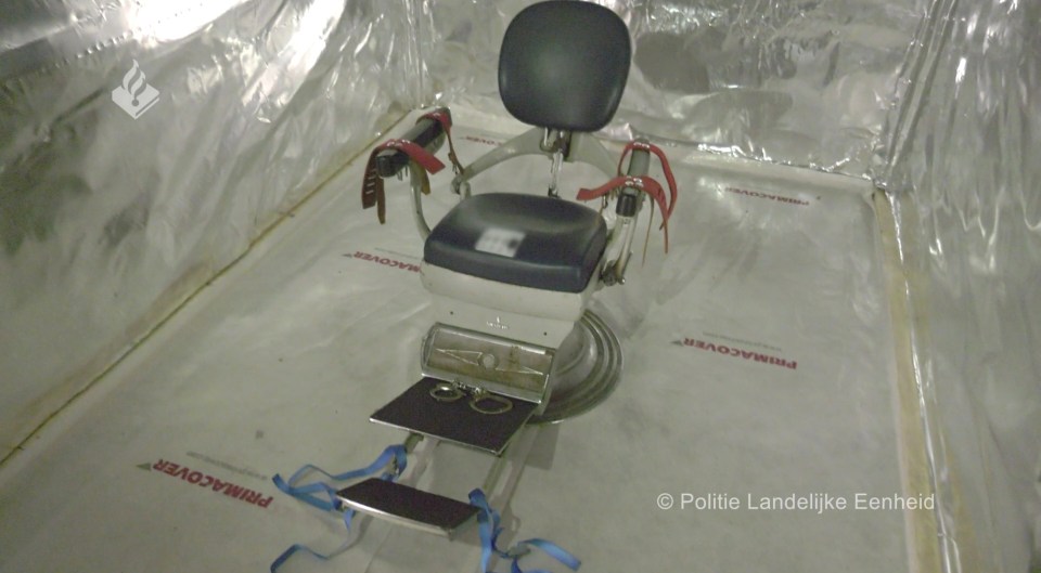 A restraint chair with handcuffs on a tray.
