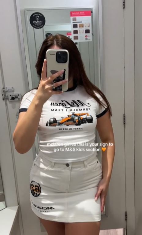 Woman modeling McLaren-themed top and skirt from M&S kids section.