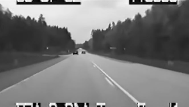 Black and white dashcam footage of a highway.