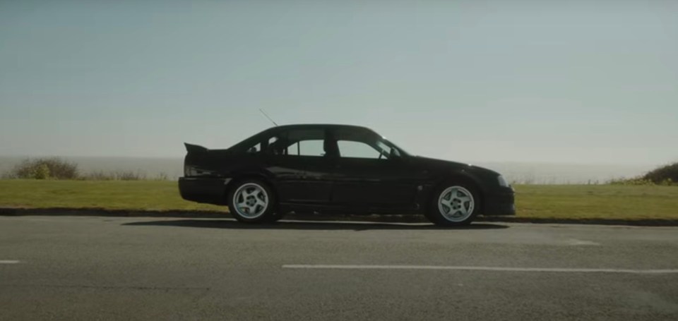 Black Super Saloon parked by the coast.