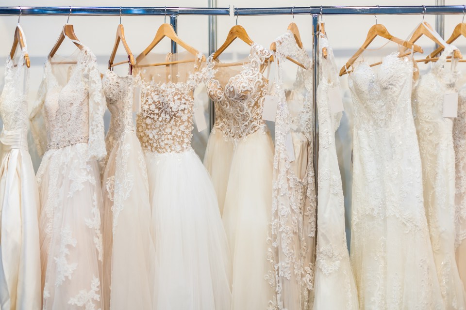 Several wedding dresses hanging in a bridal shop.